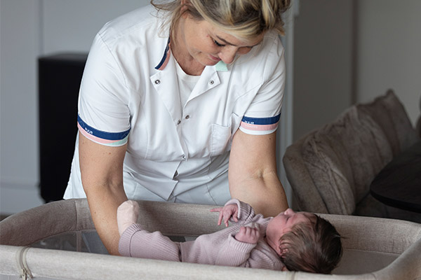 Kraamverzorgende Chantal legt baby in wieg Kraamverzorgende Chantal legt baby in wieg