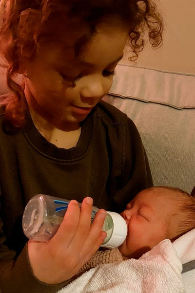 Nori geeft baby Yumi de fles foto van zus Nori die baby Yumi de fles geeft